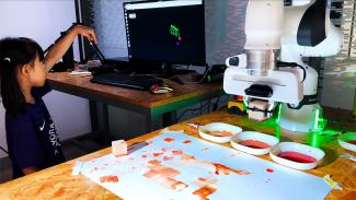 A girl raising her hand in front of the computer