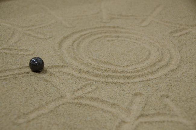 A black circle shape robot following shape on sand