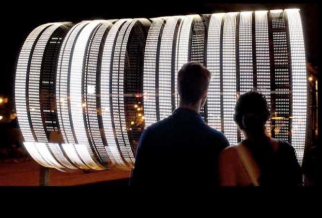 Two people watching a lighted structure 