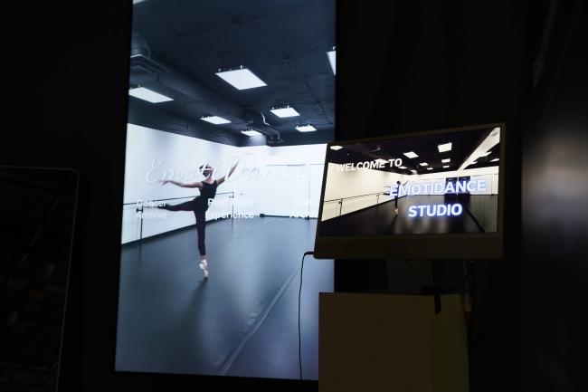 The main vertical screen (left) is the interactive display where users explore the system. The smaller monitor (right) acts as a reception-style entrance screen, introducing visitors to the concept of EmotiDance Studio.