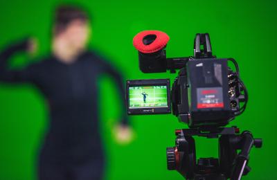 An actor against a green screen with camera rolling