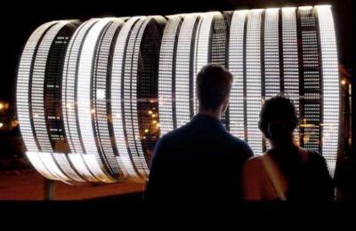 Two people watching a lighted structure 